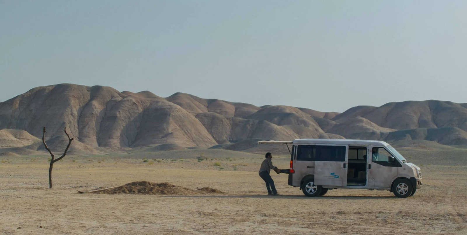 A man drags a body out of the back of a truck, with ground dug up nearby, in It Was Just An Accident