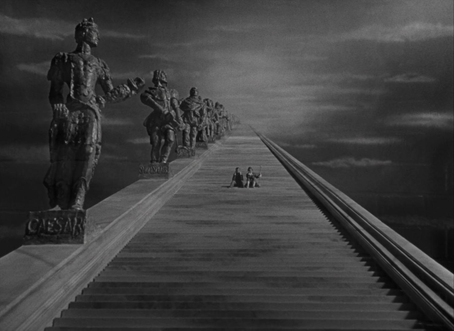 In A Matter of Life and Death, two figures sit on a stairway to heaven, with giant statues on one side