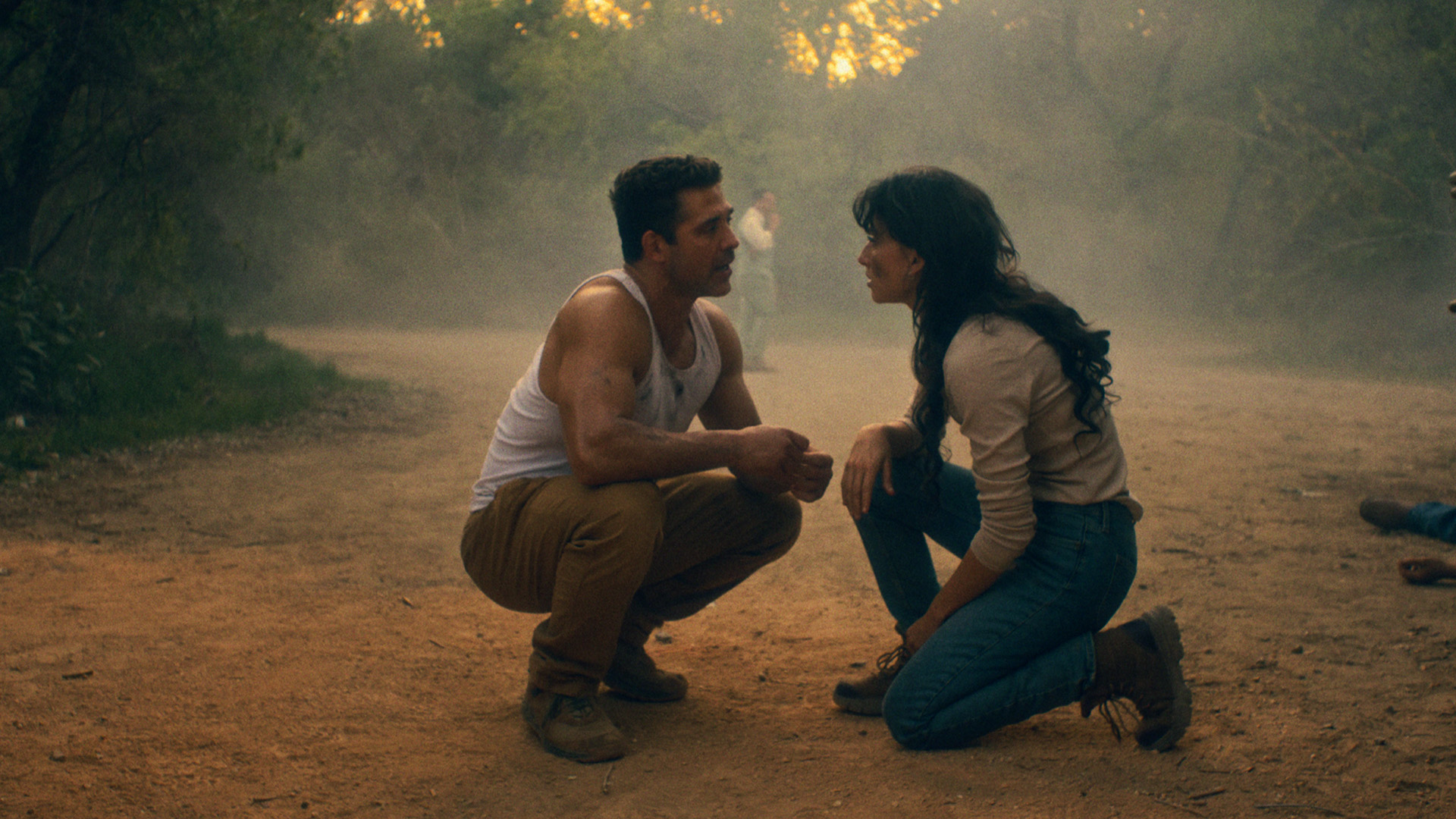 Bren Foster and Tania Raymonde squat and kneel in the dirt while talking in Mexicali
