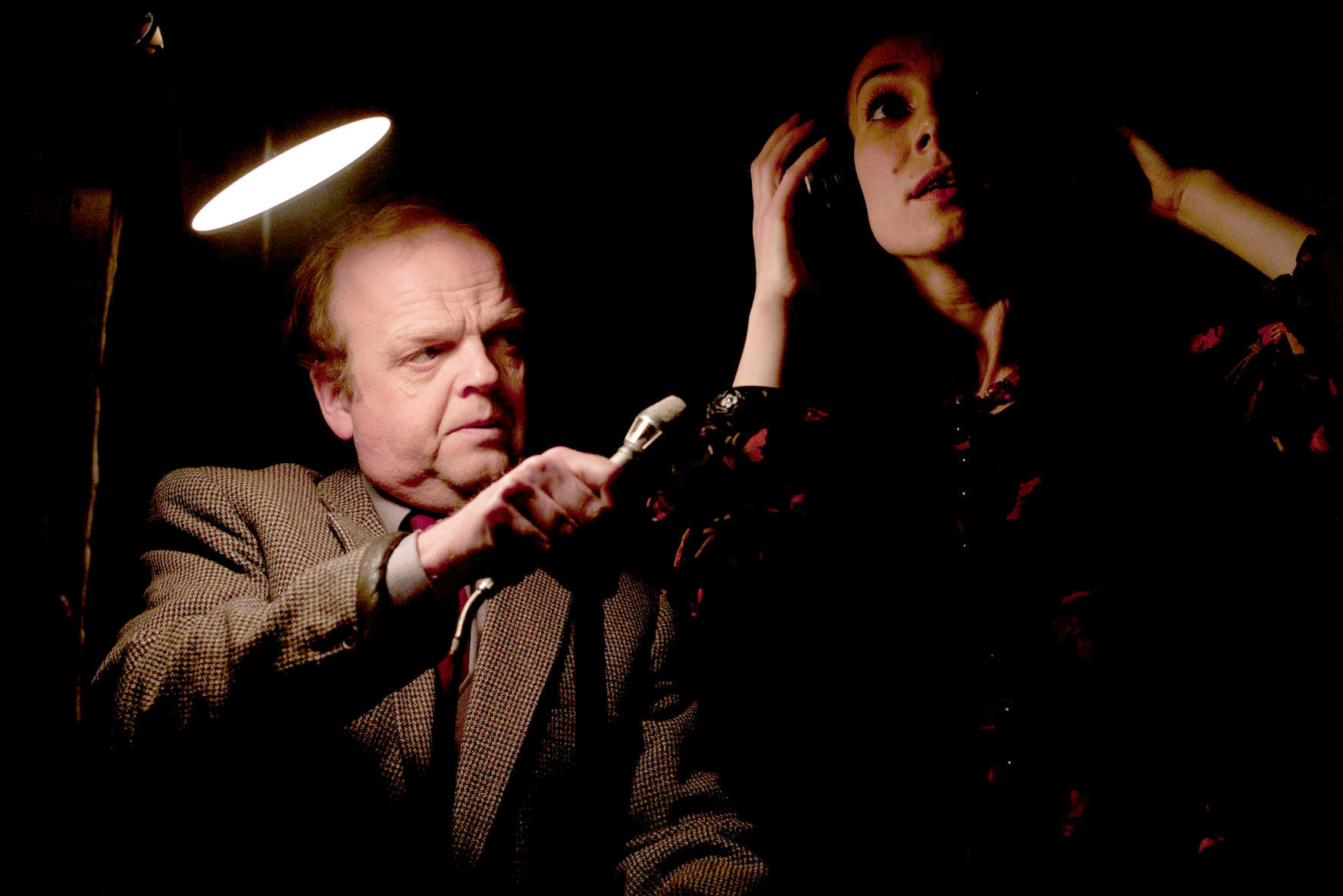 Toby Jones holds up a microphone to a woman wearing headphones in Berberian Sound Studio