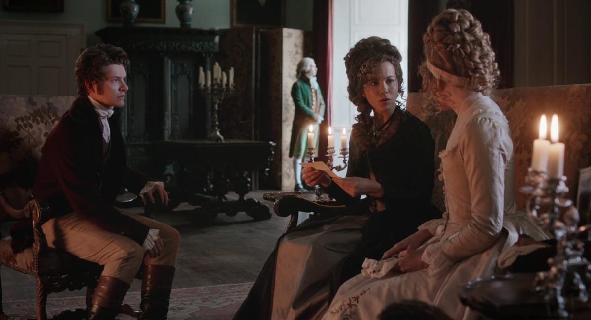 Kate Beckinsale as Lady Susan in Love & Friendship, reading a letter while sitting next to Xavier Samuel and Emma Greenwell