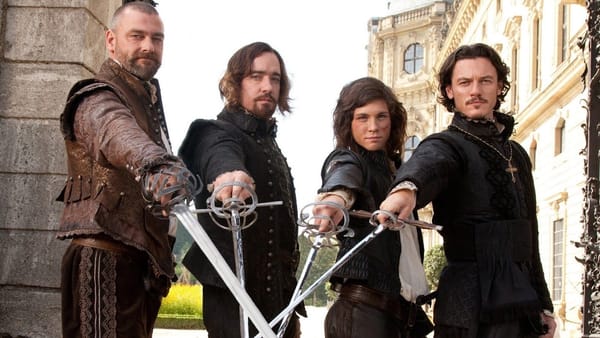 The musketeers in The Three Musketeers (2011) cross their swords and look at the camera