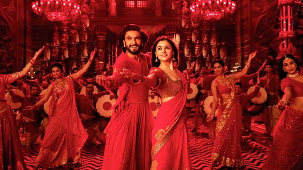 In an imaged tinted with red lighting, the leads of Rocky Aur Rani Kii Prem Kahaani dance in an ornate room